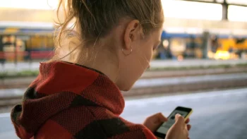 Femme qui consulte son téléphone portable sur un quai de gare