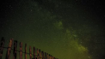 Ciel étoilé et Voie lactée au-dessus d'une clôture en bois, la nuit