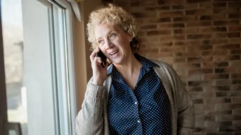 Femme souriante qui parle au téléphone près d'une fenêtre
